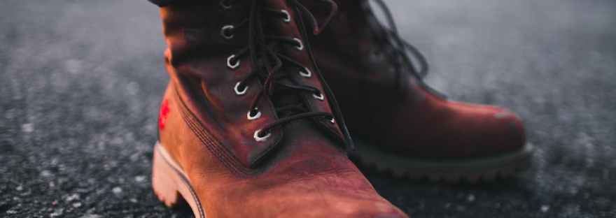 person wearing pair of brown timberland work boots and black denim skinny jeans standing on asphalt road